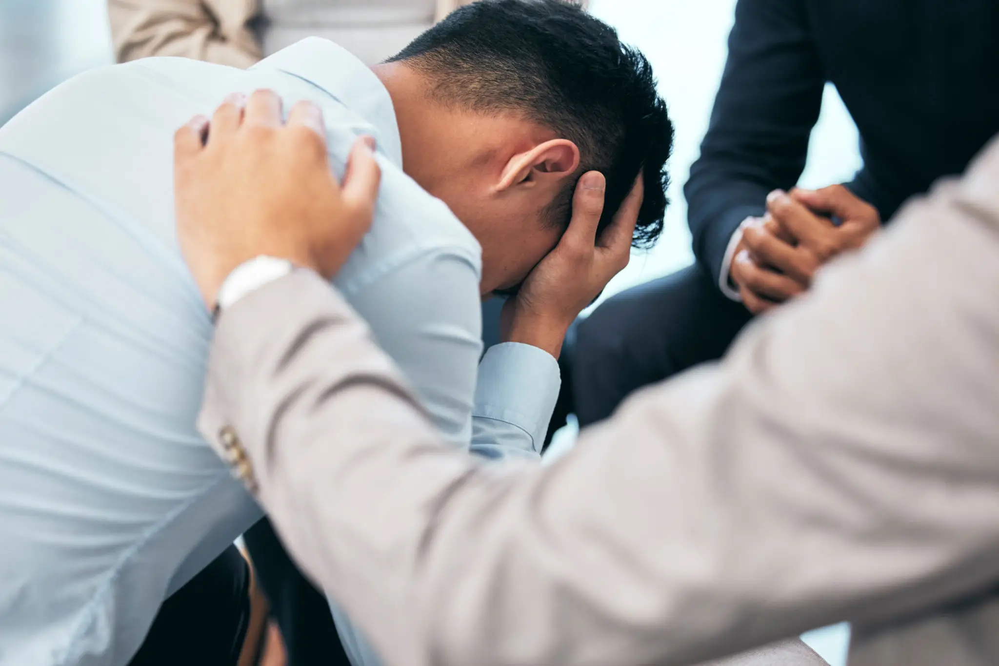 Man overwhelmed with emotions being comforted by others.