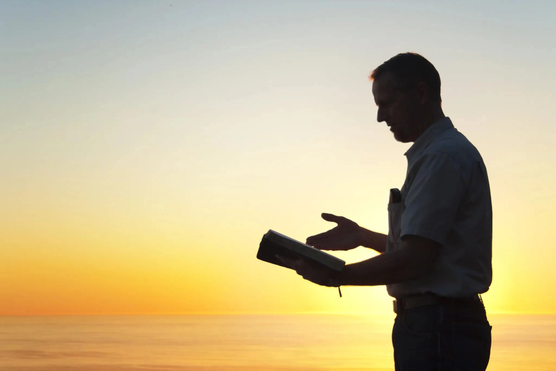 Man reading a book at sunset.