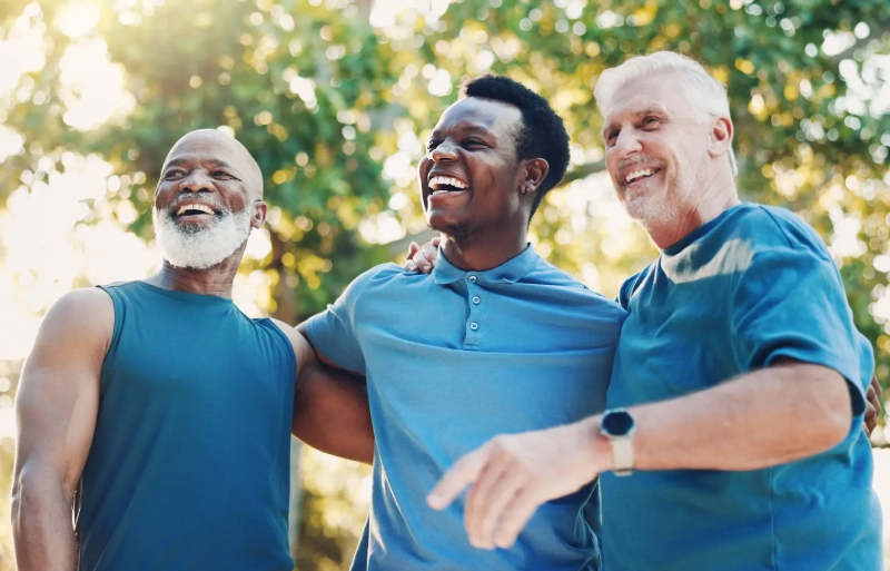 Three men smiling and enjoying a moment outdoors together.